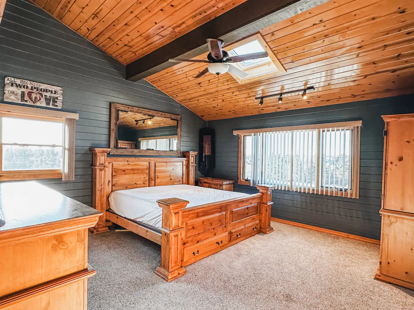 bedroom with king bed, dark blue paneling and wood ceiling